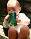 Baby drinking from a green sippy cup on a couch